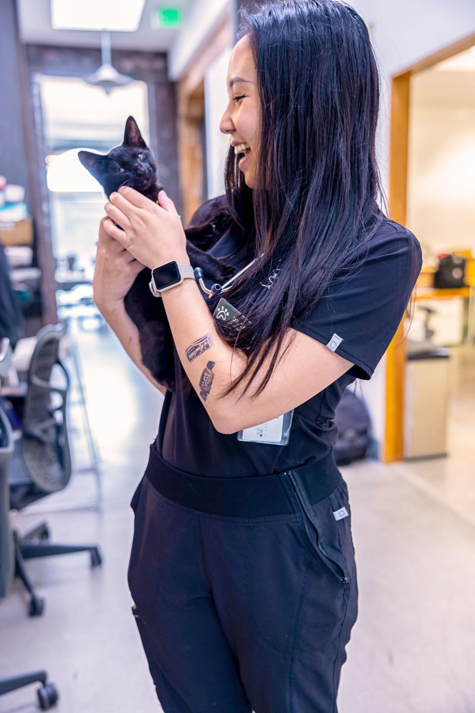 Smiling veterinary technician holding a black kitten, representing cat internal medicine services in Sherman Oaks